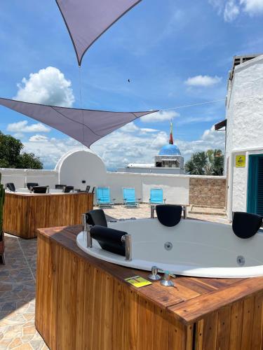 a hot tub on a deck with chairs and an umbrella at Plaza Blanca in Doradal