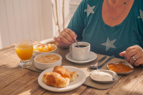 a woman sitting at a table with breakfast food at Rayentray Hostal in Puerto Madryn