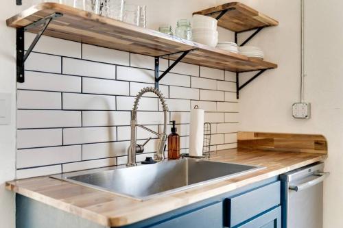 a kitchen with a stainless steel sink and wooden shelves at Historic Apt Near Music Row-Hillsboro Village in Nashville