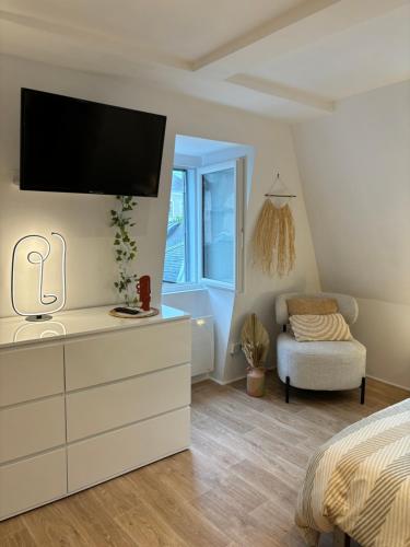 - une chambre avec une commode et une télévision murale dans l'établissement Chez Léo - Rue de la Scellerie, à Tours