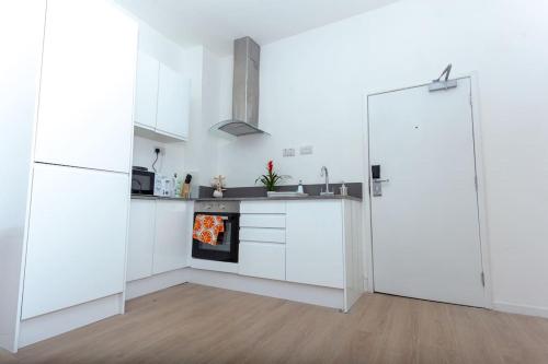 a white kitchen with white cabinets and a refrigerator at Flat 403 One bedroom apartment in Birmingham