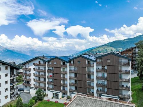 an apartment building with mountains in the background at Apartment Genets 150 D by Interhome in Nendaz