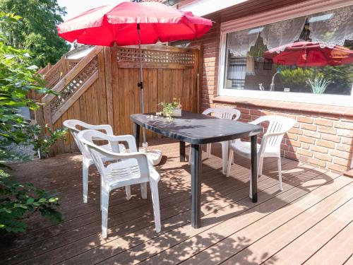 una mesa y sillas en una terraza con una sombrilla roja en Holiday Home Müter by Interhome, en Norddeich
