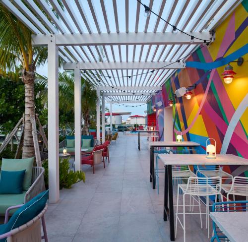 a patio with tables and chairs and a colorful wall at citizenM Miami South Beach in Miami Beach