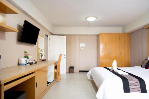a hotel room with two beds and a desk with a television at P-Park Hotel Bangkok in Bangkok