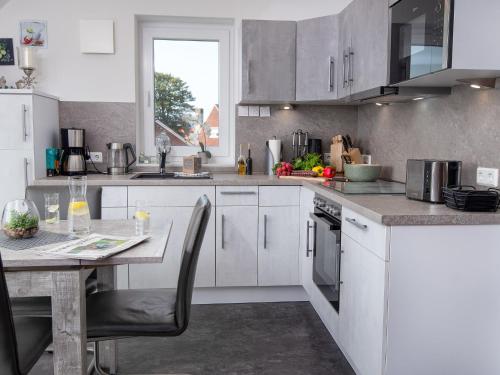 a kitchen with white cabinets and a table with chairs at Apartment Nordsee Brise by Interhome in Norden