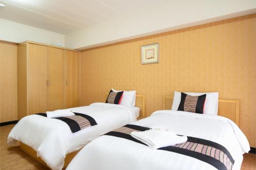 two beds in a hotel room with white sheets at P-Park Hotel Bangkok in Bangkok