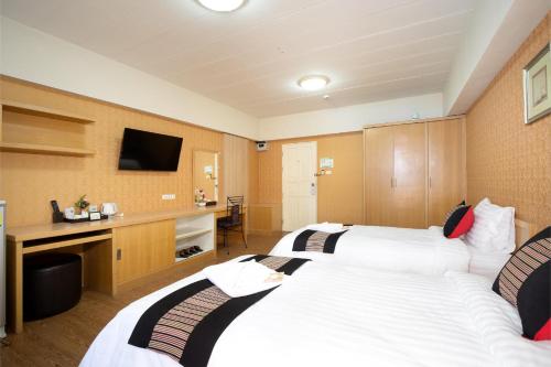a hotel room with two beds and a television at P-Park Hotel Bangkok in Bangkok