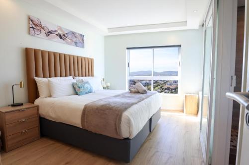 a bedroom with a large bed and a large window at Portico 1006 Beachfront Apartment with Panoramic Views in Cape Town