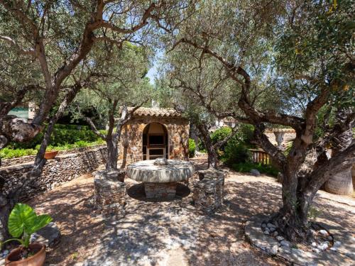 a garden with a stone table and trees at Villa Les Oliveres by Interhome in Llança