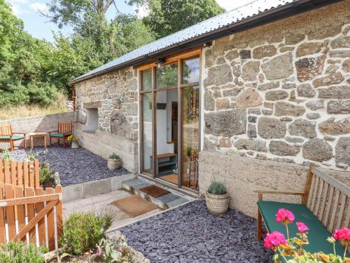 a stone cottage with a patio and a fireplace at Lingcombe Barn in Chagford