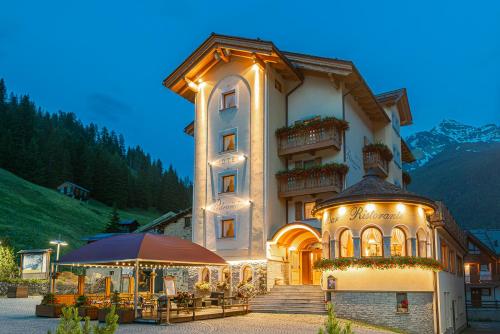 a large building with a table and an umbrella at Hotel Pedranzini in Santa Caterina Valfurva