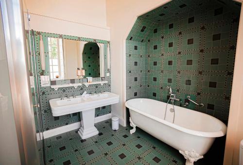 a green tiled bathroom with a tub and a sink at Château De Noirieux in Briollay