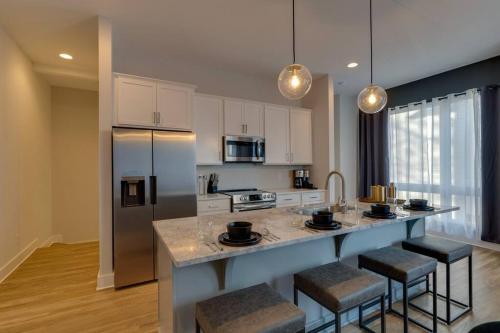 Una cocina con una encimera con taburetes y un refrigerador. en Lovely Rooftop-Game Room-Sleep 8, Near The Opry, en Nashville
