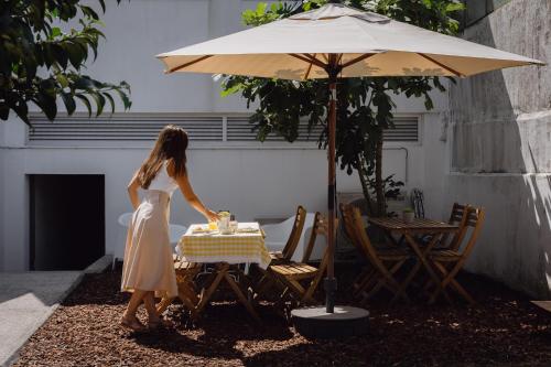 a woman in a dress cutting a cake at a table with an umbrella at Feel Porto Corporate Housing Marquês in Porto