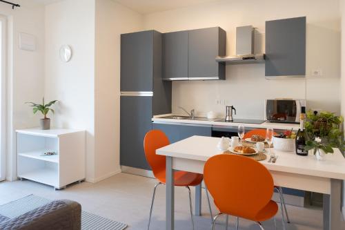 a kitchen with a white table and orange chairs at Civetta BLU, Blue Owl Apartments in Trento