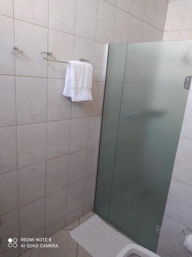 a bathroom with a shower with a toilet and a towel at Pindorama Golden Plaza Hotel - Pindorama SP in Catanduva