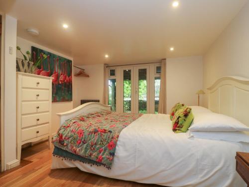 a bedroom with a large white bed and a dresser at Hillcroft in St Austell