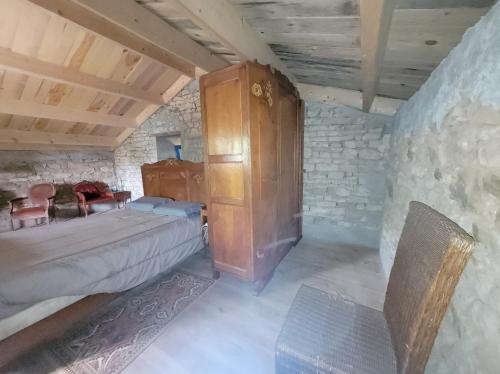 une chambre avec un lit et une armoire en bois dans l'établissement Nuit insolite, chambre au dessus d'une étable, à La Chapelle-Thémer