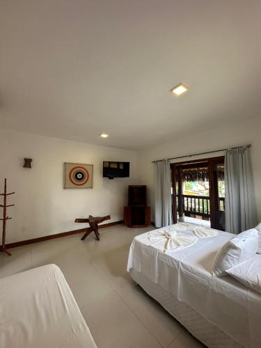 a bedroom with a large white bed and a television at Pousada Porto da Barra in Barra Grande