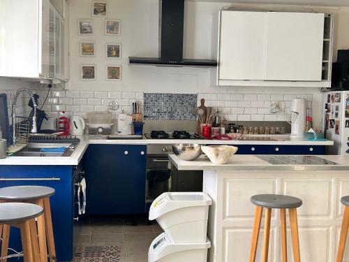 une cuisine avec des placards bleus et blancs et des tabourets de bar dans l'établissement Appartement avec terrasse proche centre ville d'Arles, à Arles