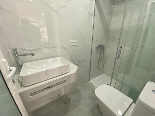 a white bathroom with a sink and a shower at Alaram Holidays House in Arguineguín