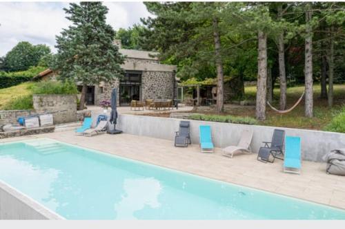 una piscina con sedie e tavolo e un edificio di A la ville comme à la campagne a Taulhac-près-le-Puy