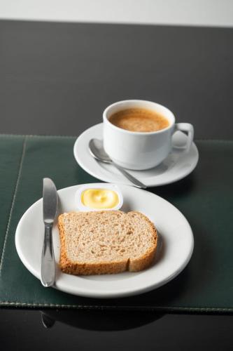 a plate with a sandwich and a cup of coffee at Olavo Bilac Hotel in Taubaté
