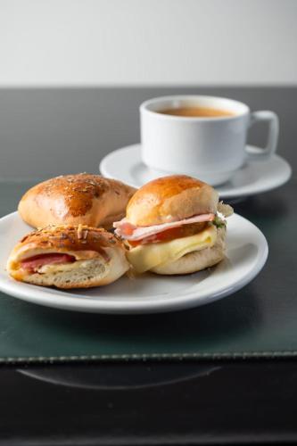 two sandwiches on a plate with a cup of coffee at Olavo Bilac Hotel in Taubaté