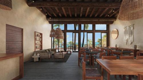 a restaurant with wooden tables and chairs and windows at Secrets Tulum Resort & Beach Club - Adults Only - All Inclusive in Tulum