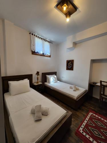 two beds in a room with white walls at Sokak Boutique Hotel in Berat