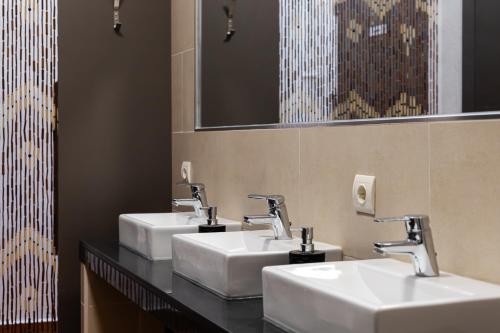 three sinks in a public bathroom with mirrors at Hostal Entrecaminos in Ardales