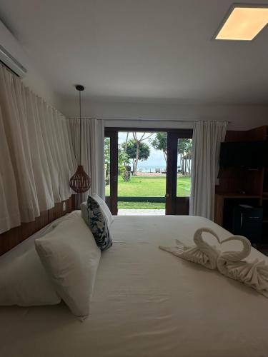 a bedroom with a large white bed with a window at Pousada Porto da Barra in Barra Grande