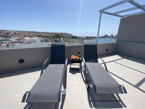 a balcony with two benches and a view of a city at Alaram Holidays House in Arguineguín