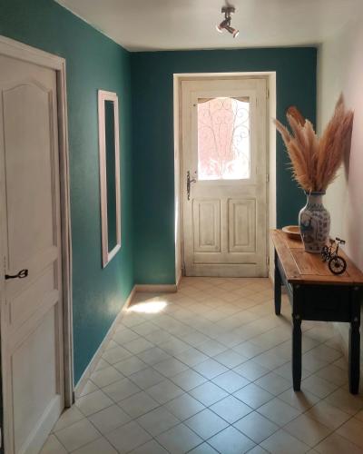 un couloir avec une porte et un vase sur une table dans l'établissement Welcome, Bienvenue, Chez Charly!, à Nébian