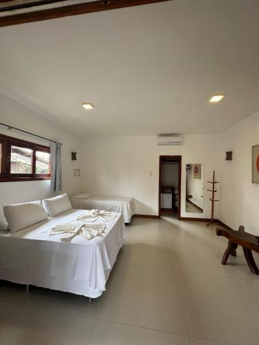 two beds in a room with white walls at Pousada Porto da Barra in Barra Grande