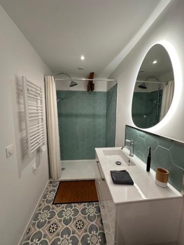 a bathroom with a sink and a shower with a mirror at Les jardins de Reville in Réville