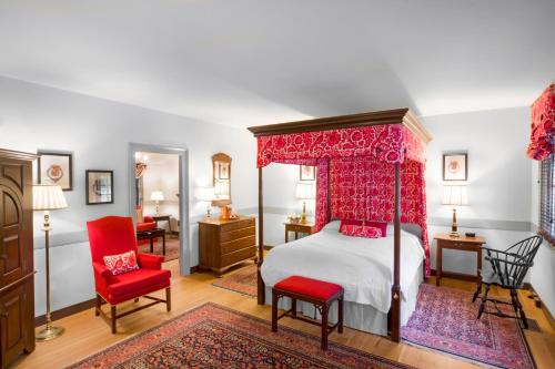 a bedroom with a canopy bed and red chairs at Colonial Houses, an official Colonial Williamsburg Hotel in Williamsburg