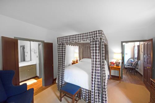 a bedroom with a canopy bed and a blue chair at Colonial Houses, an official Colonial Williamsburg Hotel in Williamsburg