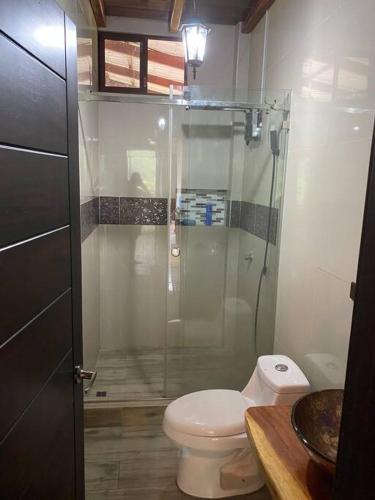 a bathroom with a toilet and a glass shower at Paraíso selvático Casa de campo in Sucúa