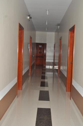 an empty hallway with wooden doors and a tile floor at Hotel Coca Imperial in Puerto Francisco de Orellana
