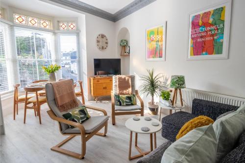 Una sala de estar con un sofá y sillas y una mesa. en Flat 1, Church House, en Ilfracombe