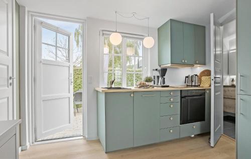 a kitchen with green cabinets and a window at Beach Front Home In Sjølund in Sjølund
