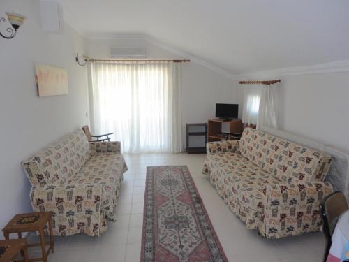 a living room with two couches and a tv at Cicek Hotel & Apartments in Fethiye