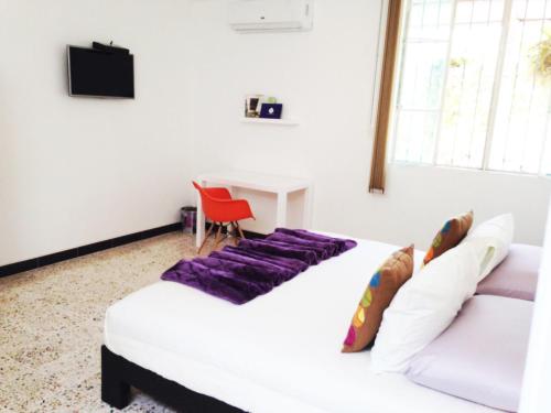 two beds in a room with a red chair and a desk at Rancho Macloy Hotel Spa & Social Events in Yautepec