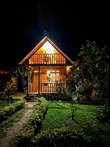 a small wooden house with a lit up facade at night at Palo Alto Lodge in Oxapampa