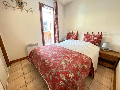 une chambre avec un lit avec une couverture rouge et une fenêtre dans l'établissement Appartement au pied des pistes avec balcon, parking et Wi-Fi - FR-1-505-143, à Notre-Dame-de-Bellecombe