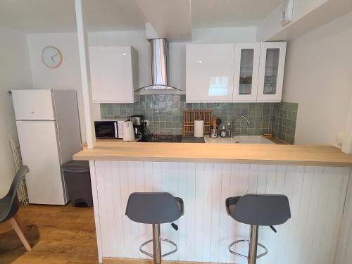 une cuisine avec deux tabourets de bar et un comptoir dans l'établissement Le Vert d'Eau - Évasion Authentique au Cœur de Dieppe, à Dieppe