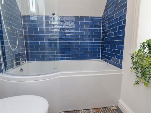 a blue tiled bathroom with a tub and a toilet at Bobbies' Retreat, 20 High Street in Bridlington