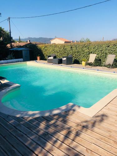 une piscine d'eau bleue et une terrasse en bois dans l'établissement Villa tout confort Piscine et Spa Côte d'Azur 6 personnes, à Puget-sur Argens